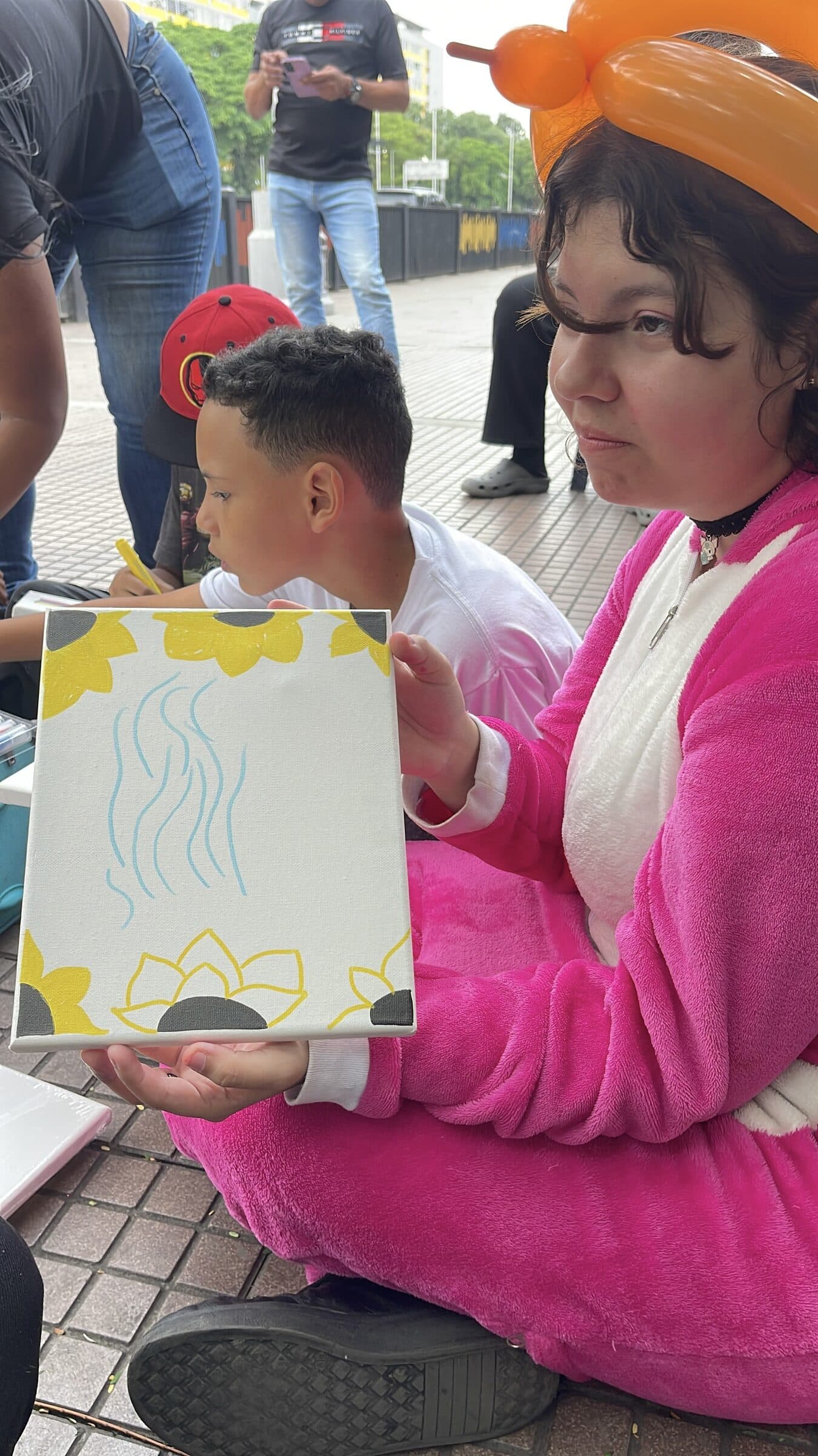 A teenager shows her sunflower canvas painted during the camp art workshop.