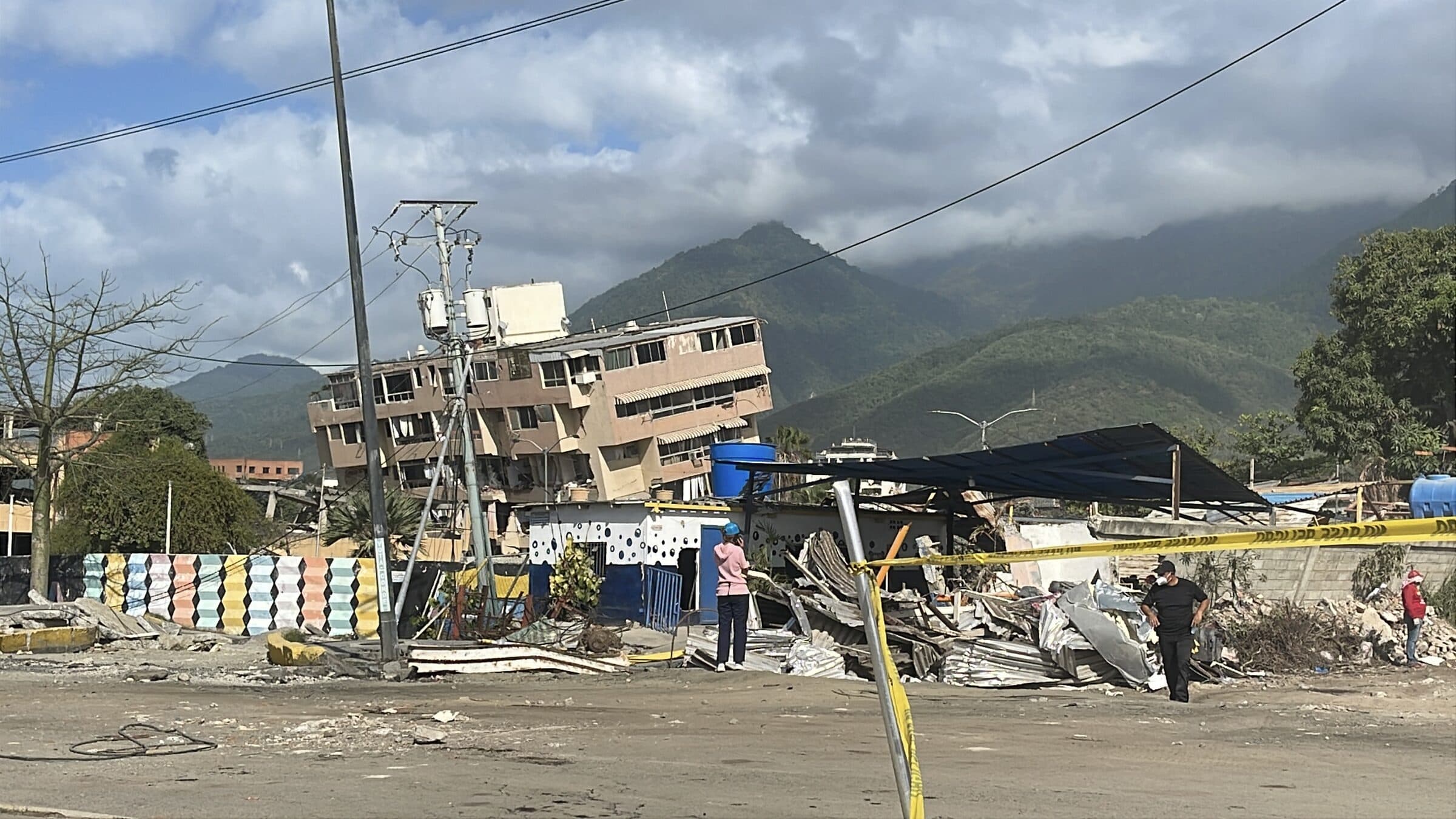 Workers assess a tilted earthquake-damaged building behind a safety cordon in La Guaira, Venezuela.