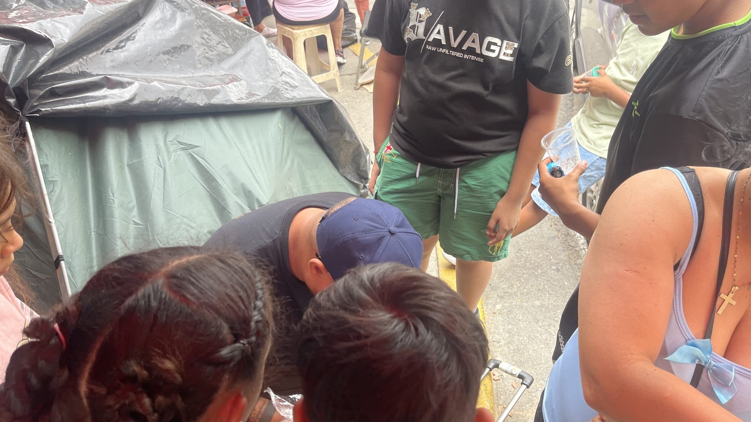An open suitcase filled with hygiene supplies as an IHE volunteer distributes them to children at the camp.