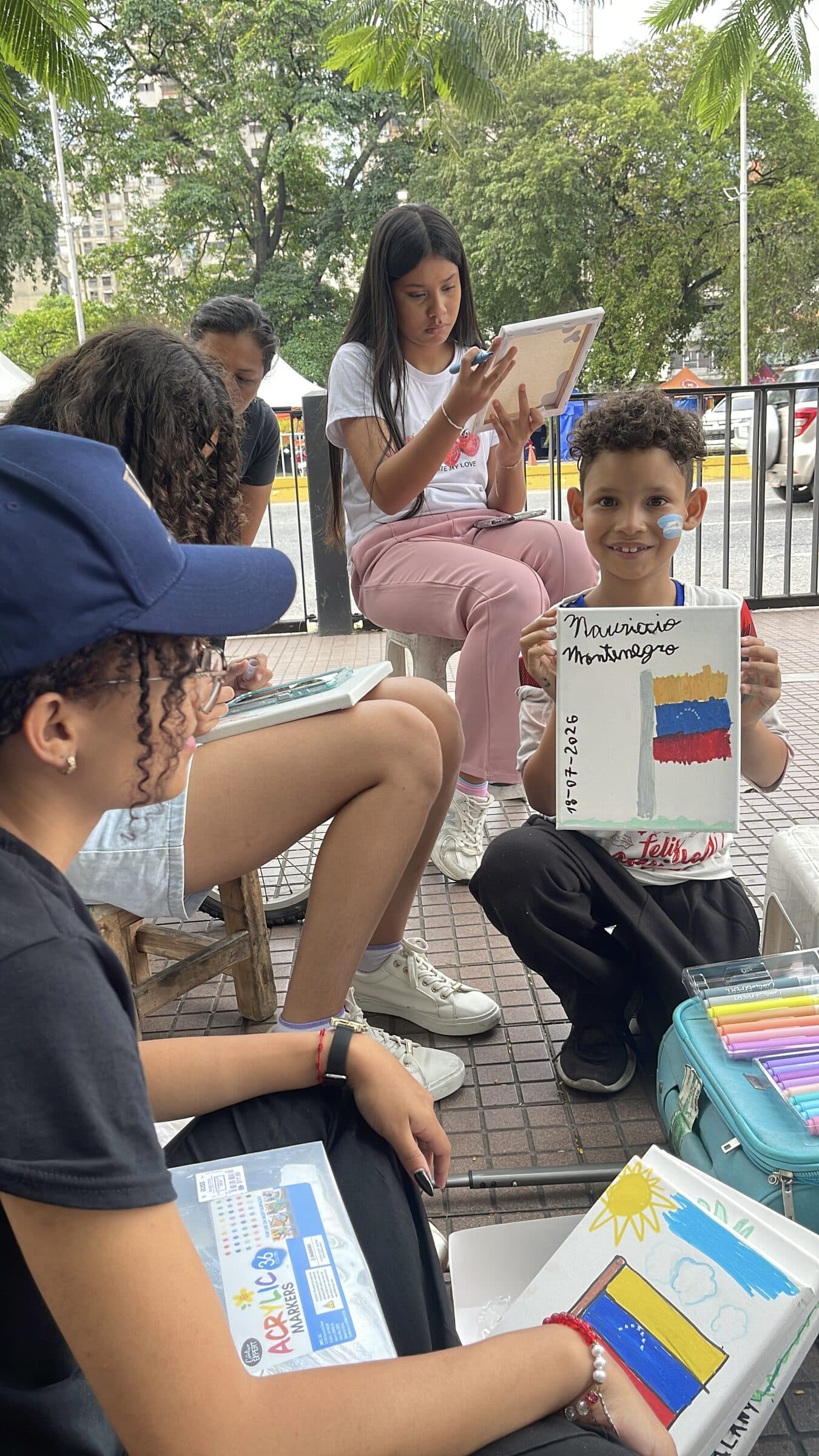 A smiling boy shows the camera his signed painting of the Venezuelan flag at the camp art workshop.