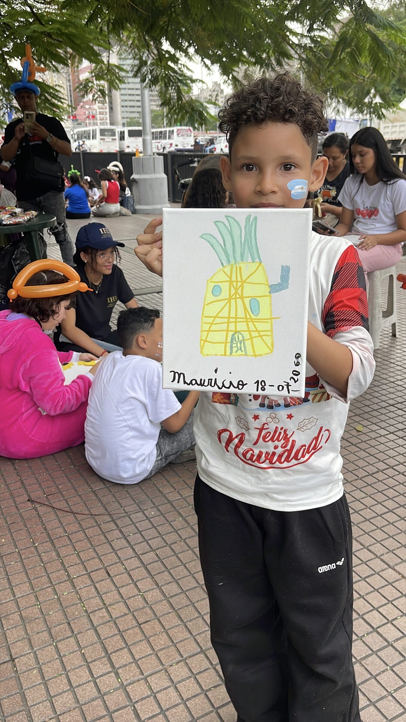 A boy proudly holds up his pineapple painting during the IHE art workshop.