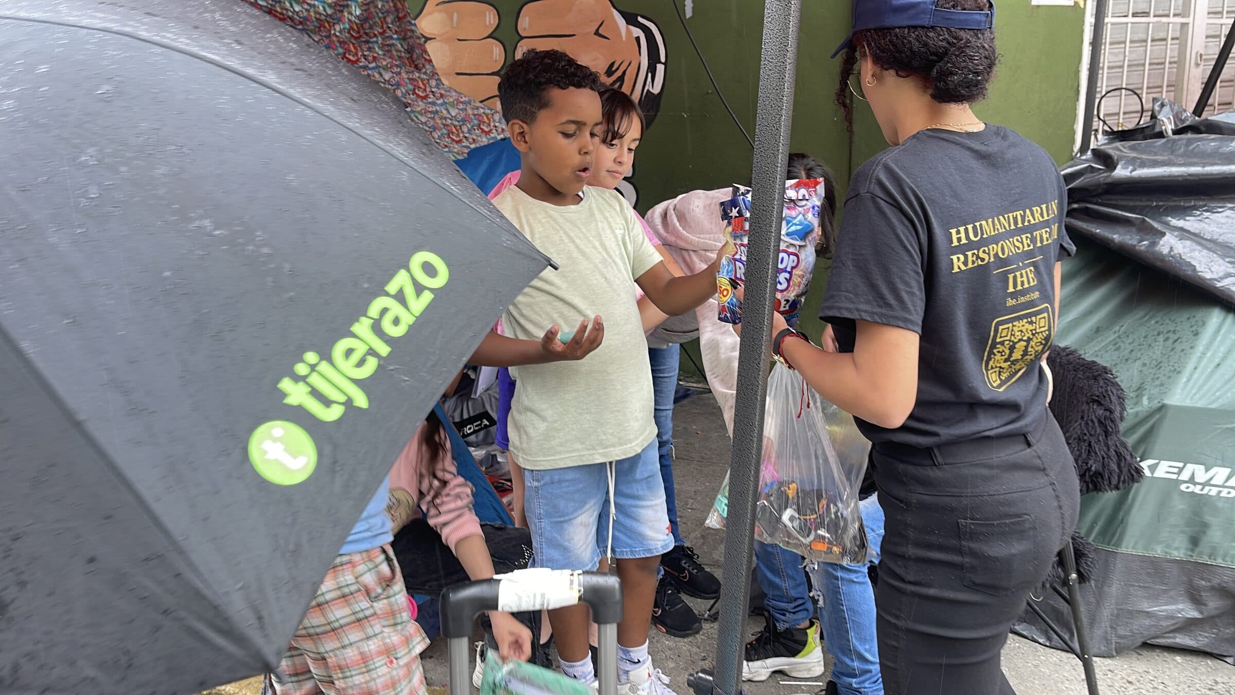 A boy receives toys and sweets with both hands during an IHE distribution at the camp.